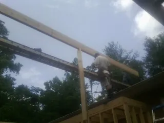Carpenter setting a ridge beam over a new addition frame — Ice Dam Removal by Roofing Brothers in Gowrie