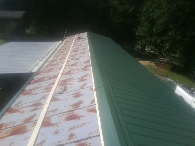 Old rusted panels beside newly installed green metal roofing — Wind Damage Roof Repair by Roofing Brothers in Gowrie
