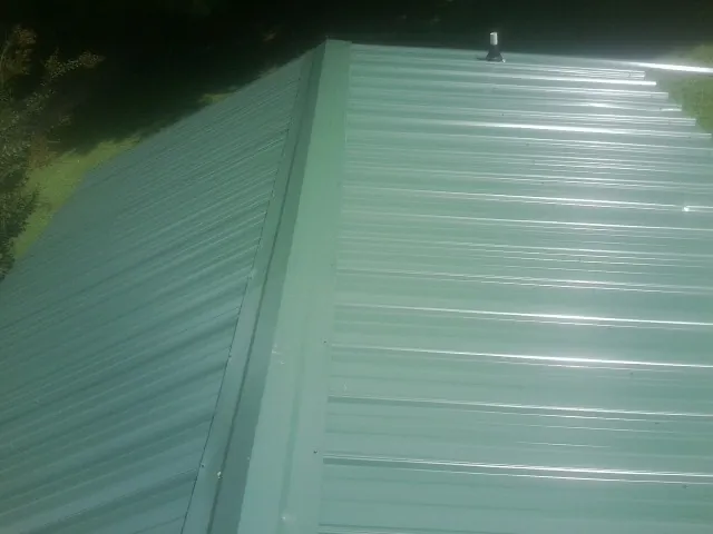 New green metal panels meeting at the ridge of a roof — Flat Roof Repair work by our crew in Gowrie