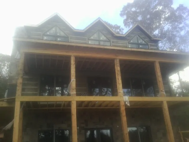 Dormers and porch framing on a large log home under construction — Roof Coating work by our crew in Gowrie