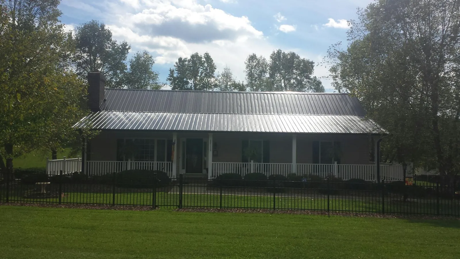 Gray metal roof on a brick ranch with a full width front porch — Gutter Guard Installation work by our crew in Gowrie