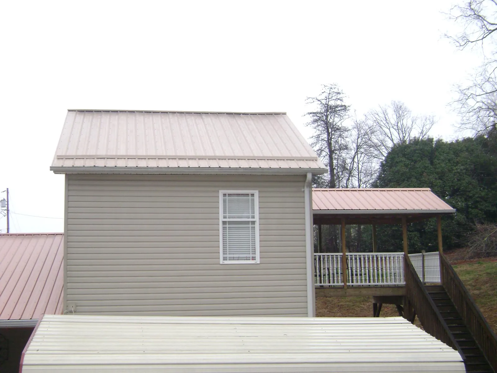 Tan metal roofs on a two story addition and attached porch, from a Roof Replacement job in Gowrie