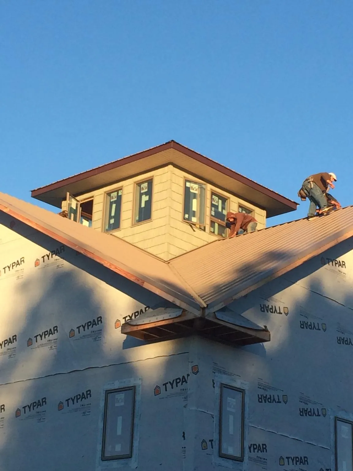 Roofers working around a rooftop cupola on a new metal roof at sunset — Roof Waterproofing in Gowrie by Roofing Brothers